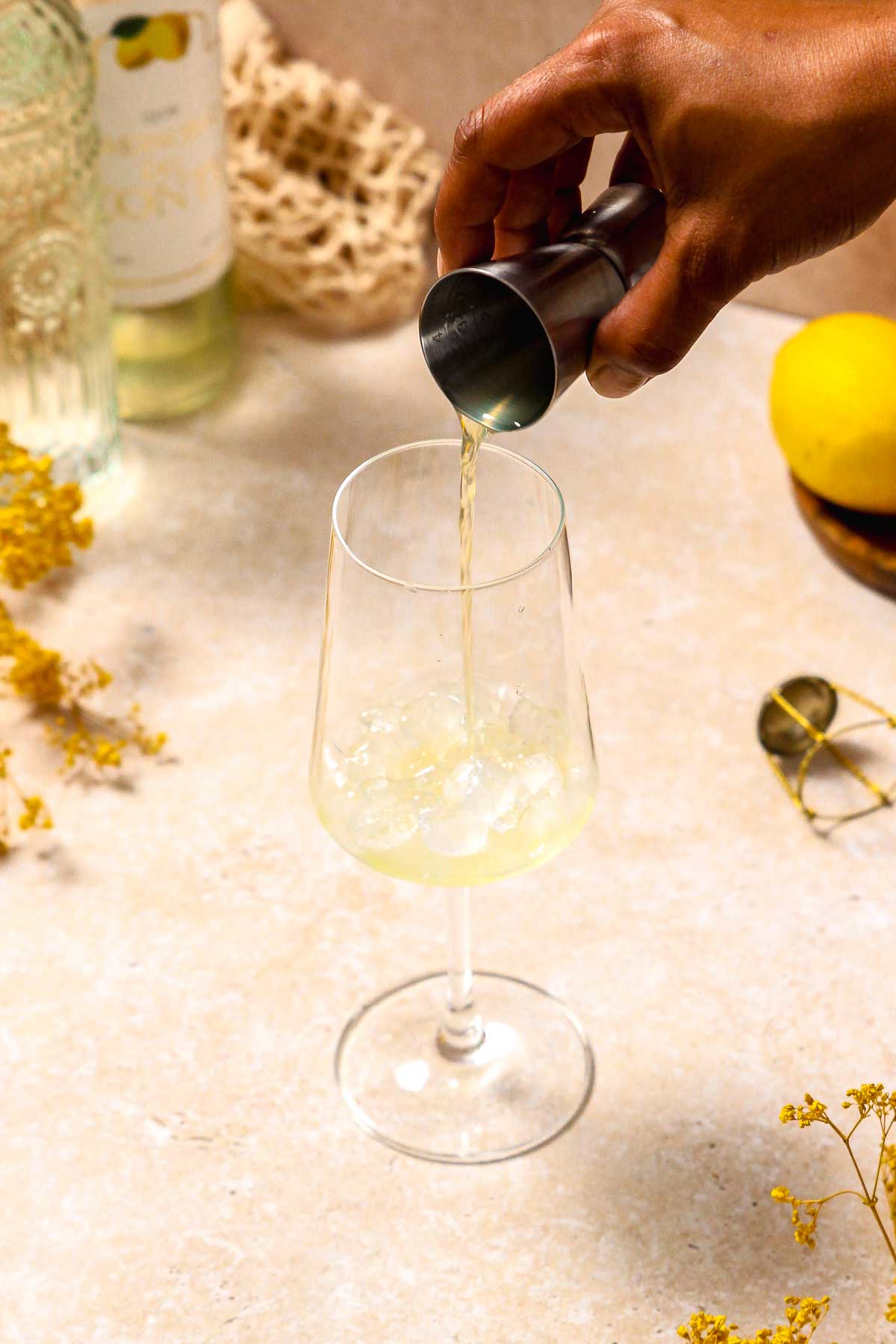 pouring limoncello into wine glass with crushed ice.