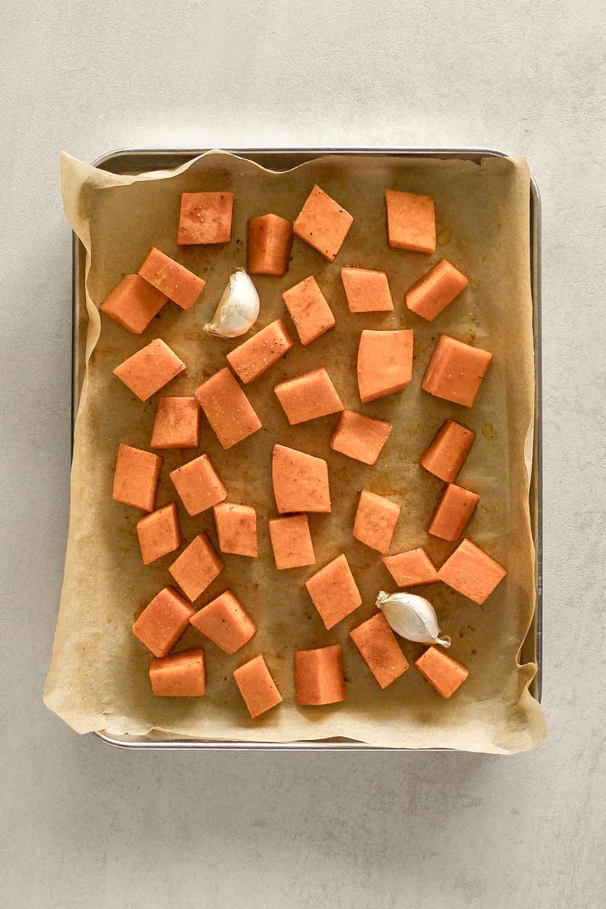 diced pumpkin and garlic on baking tray with parchment paper.