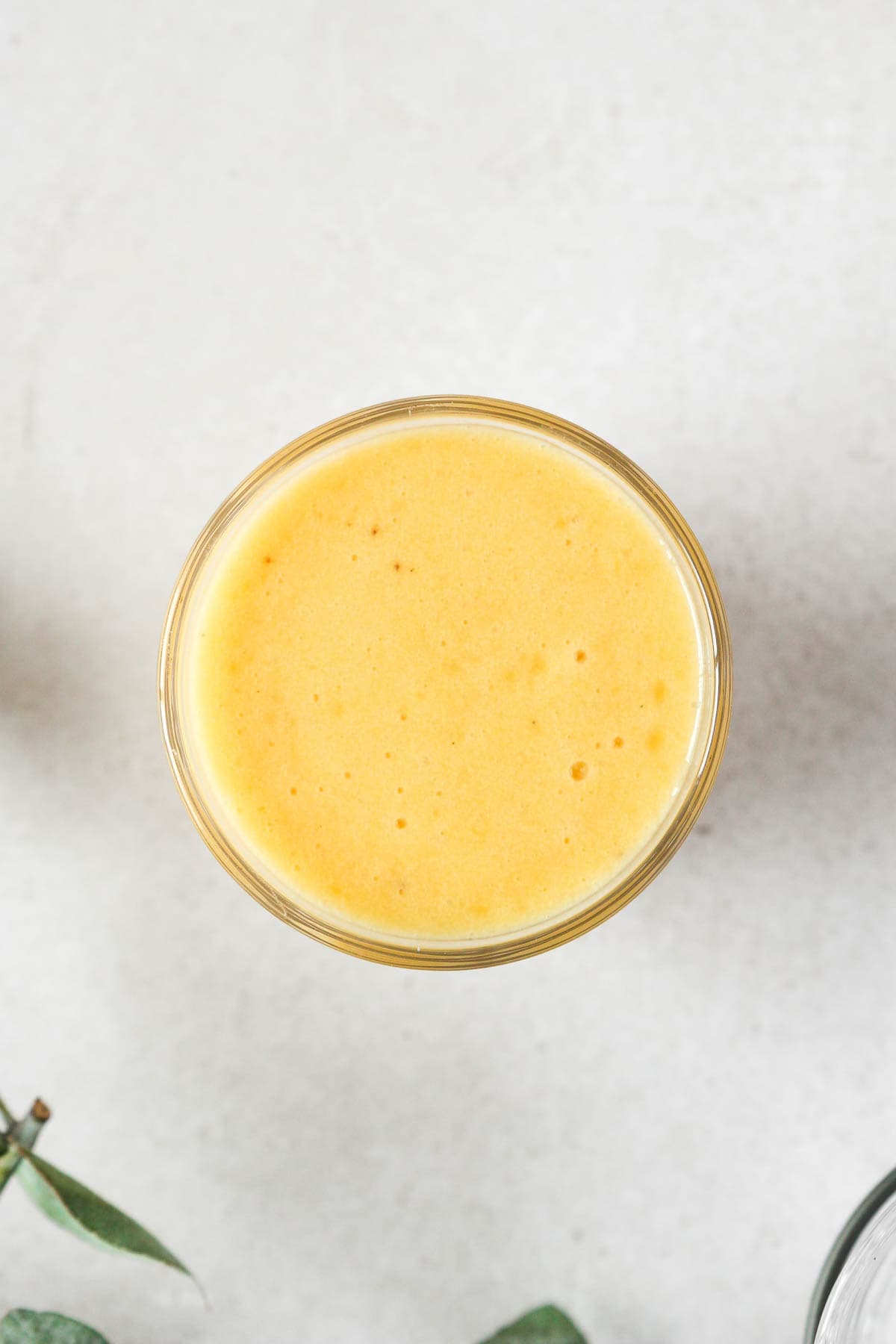 overhead shot of yellow smoothie on grey background.